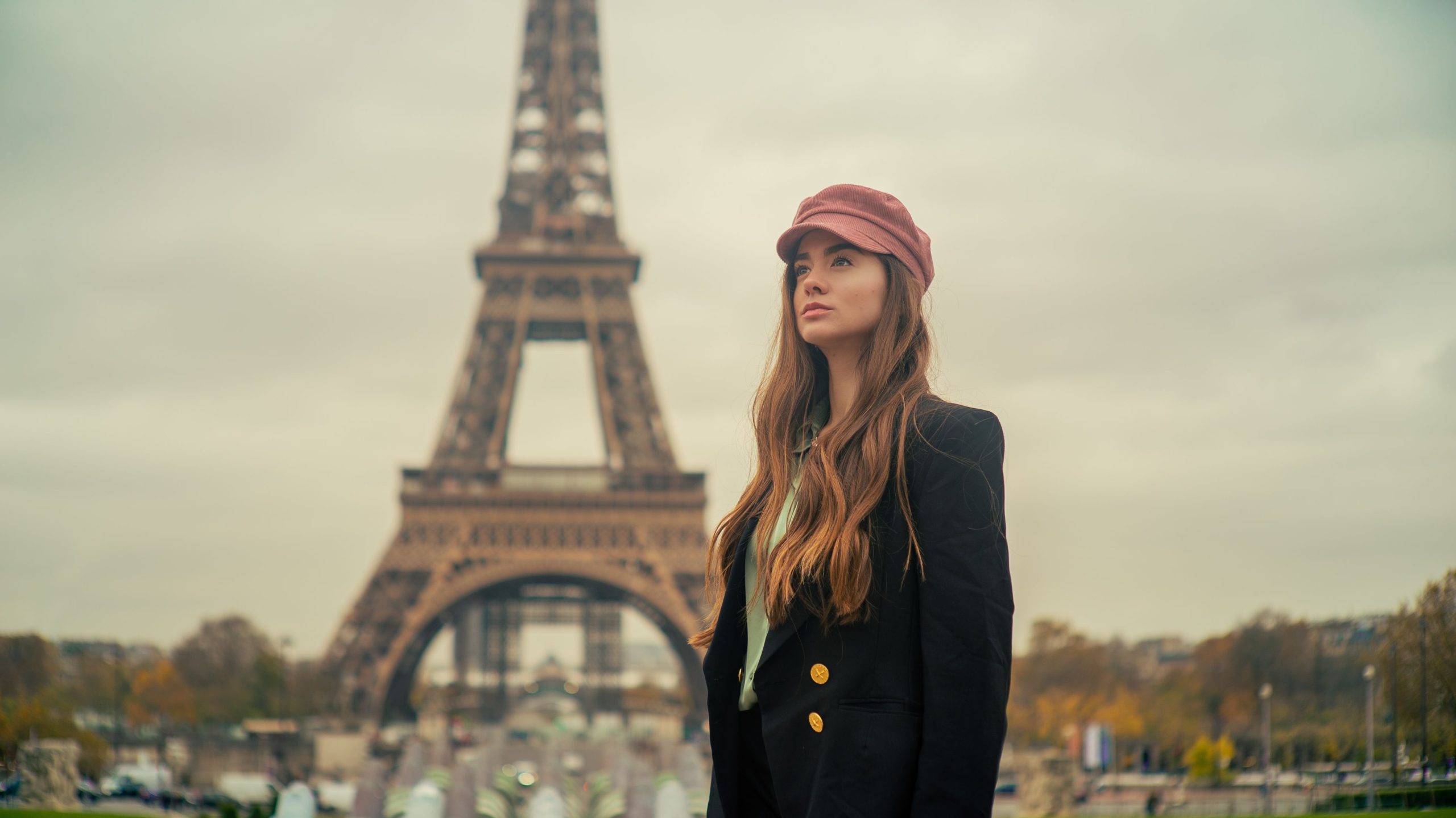 Elegant young woman in Paris posing with a chic look by the Eiffel Tower.