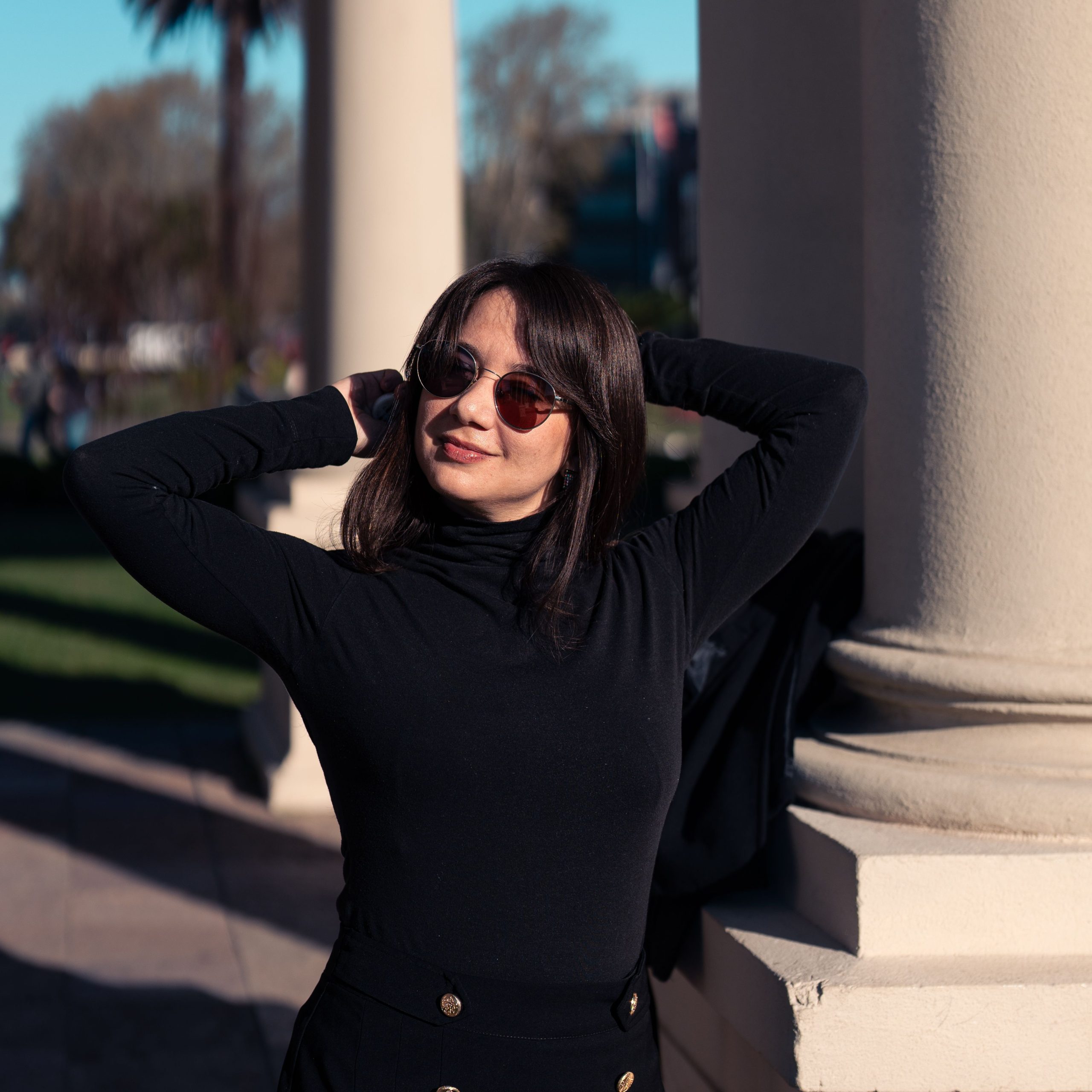 Stylish woman enjoying a sunny outdoor day by architectural columns.